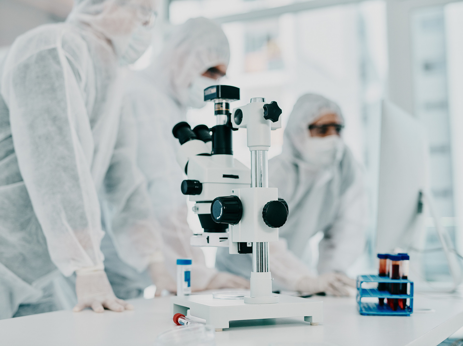 Sterile, white and modern room with a closeup of a microscope and medical scientists or group conducting research for corona. Clinical and bright laboratory with doctors working on a blood sample. The Importance of Vendor Qualification in GMP Environments
